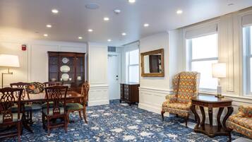 Una habitación con alfombra de diseño azul, muebles de madera, un espejo y una ventana con persianas.
