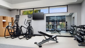 A modern gym with exercise equipment, a TV, and large windows offering a view of the outdoors. - Courtyard by Marriott Little Rock West (Little Rock)