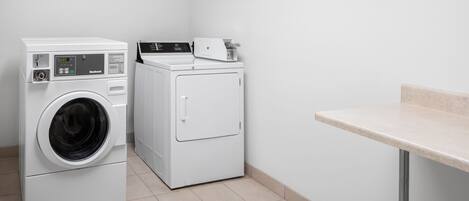 A laundry area with two washing machines, a dryer, and a countertop.