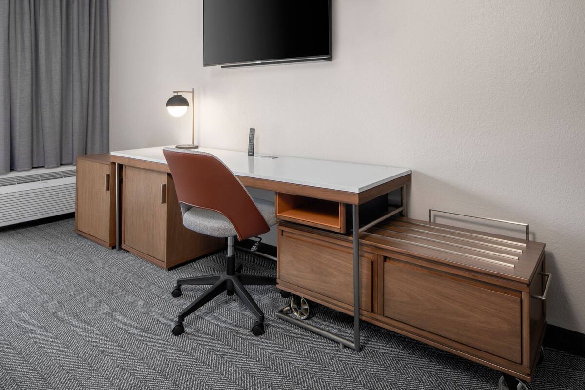 Een modern bureau met een stoel, een flatscreen televisie aan de wand en een inbouwkast.