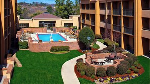 A hotel with a swimming pool, outdoor seating, and well-maintained landscaping. - Courtyard by Marriott Little Rock West (Little Rock)