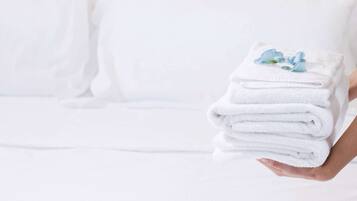 Une personne tenant une pile de serviettes blanches, avec une fleur bleue posée sur le dessus.