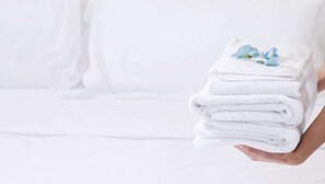 A person holding a stack of white towels with a blue flower on top. - Magnuson Hotel Bradenton (Bradenton)