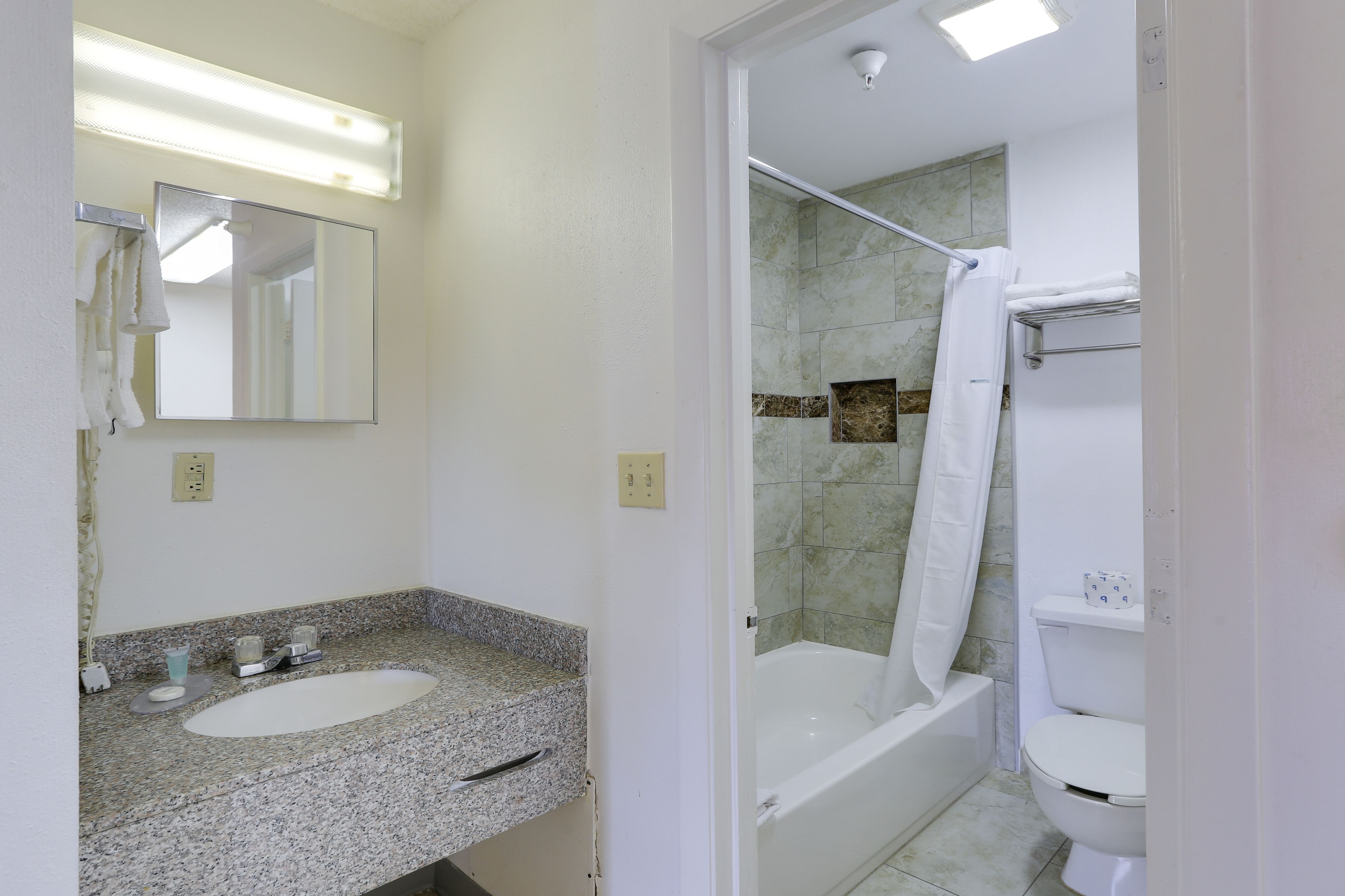 A bathroom with a granite countertop sink, a mirror, a shower with a glass door, and a toilet.