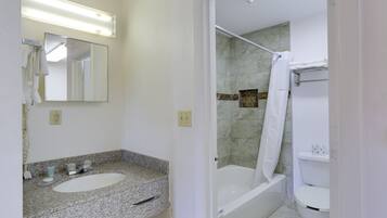 A bathroom with a granite countertop sink, a mirror, a shower with a glass door, and a toilet.