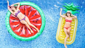 Two individuals in a swimming pool, each lying on a different inflatable float. - Magnuson Hotel Bradenton (Bradenton)