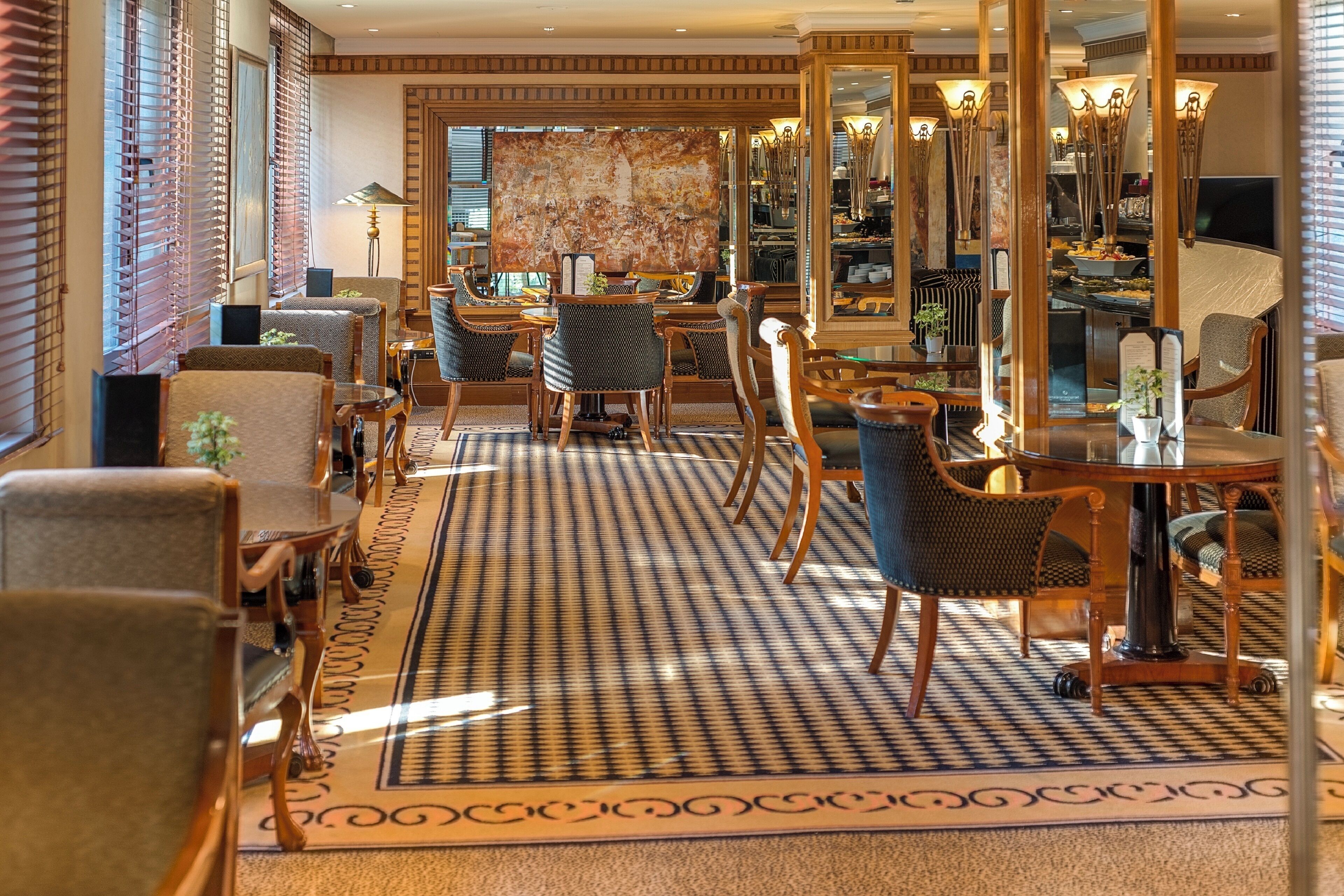 Un hall de hotel con suelo a cuadros, muebles de madera y un espejo grande.