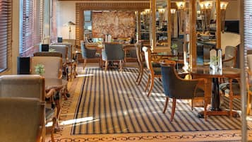 Un hall de hotel con suelo a cuadros, muebles de madera y un espejo grande.