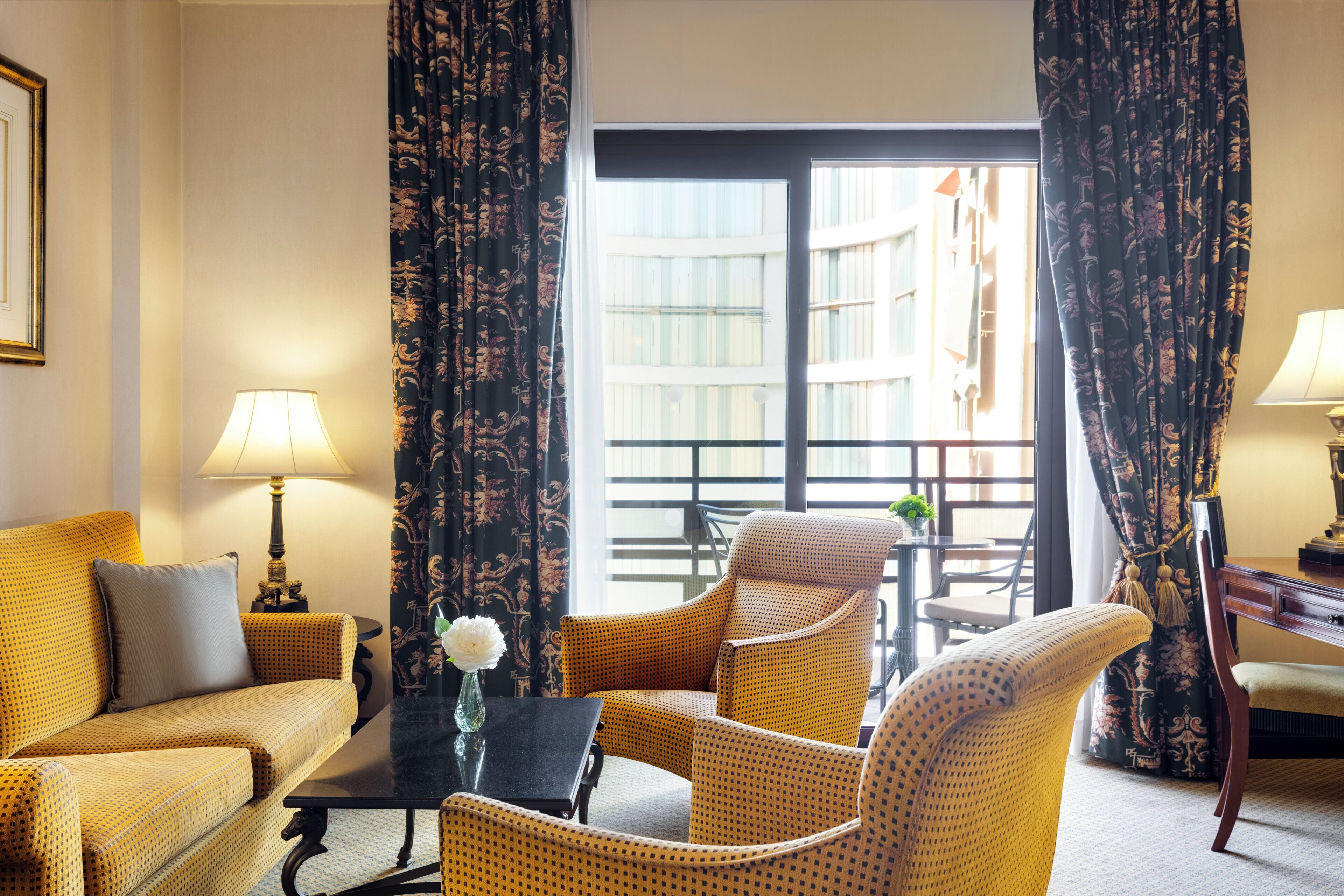 Habitación de hotel con sofá, sillones, una mesa y vistas al exterior.
