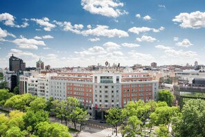 Un hôtel à plusieurs étages doté d’une cour intérieure, entouré de bâtiments urbains et d’arbres.