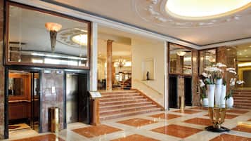 A grand lobby with marble flooring, a staircase, and a reception area.