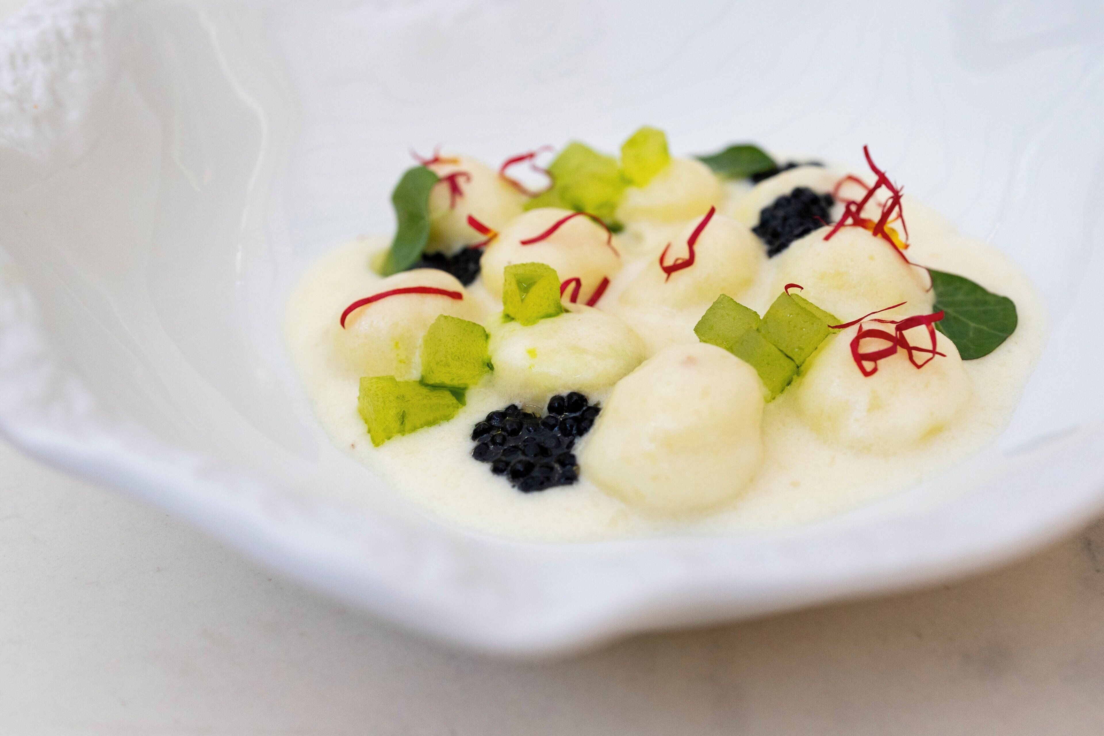 Un tazón blanco con un postre cremoso, decorado con elementos verdes y rojos.