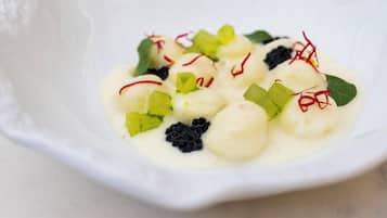 Un tazón blanco con un postre cremoso, decorado con elementos verdes y rojos.