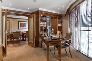 A conference room with a wooden desk, chairs, a computer, and a bookshelf.