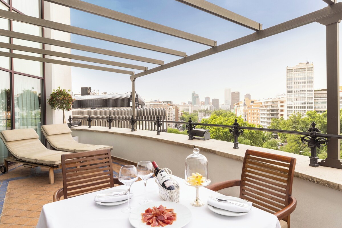 Una terraza en la azotea con una mesa lista para comer, con vista a la ciudad.