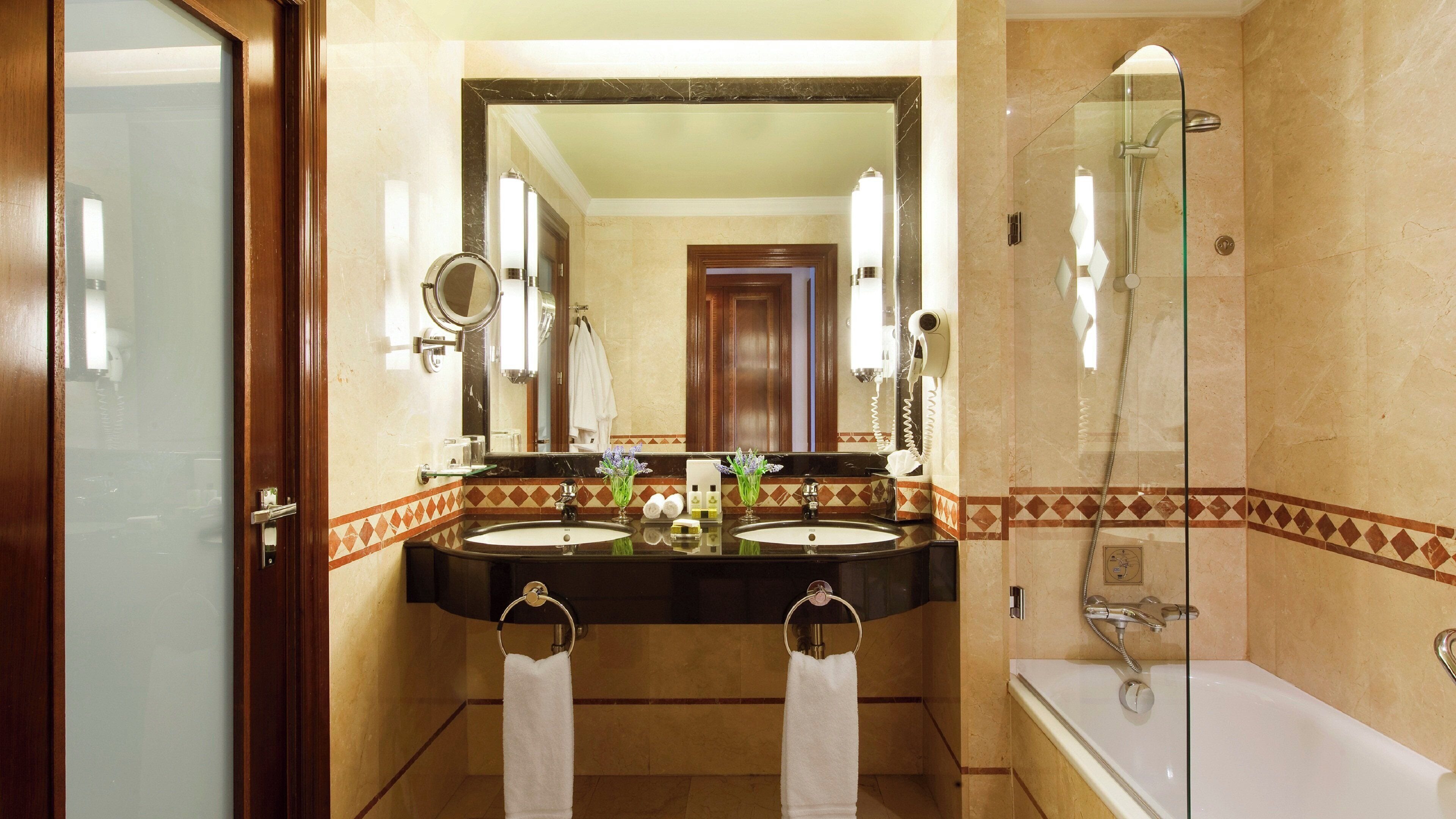 Une salle de bain avec deux lavabos, un grand miroir, une douche et une porte.