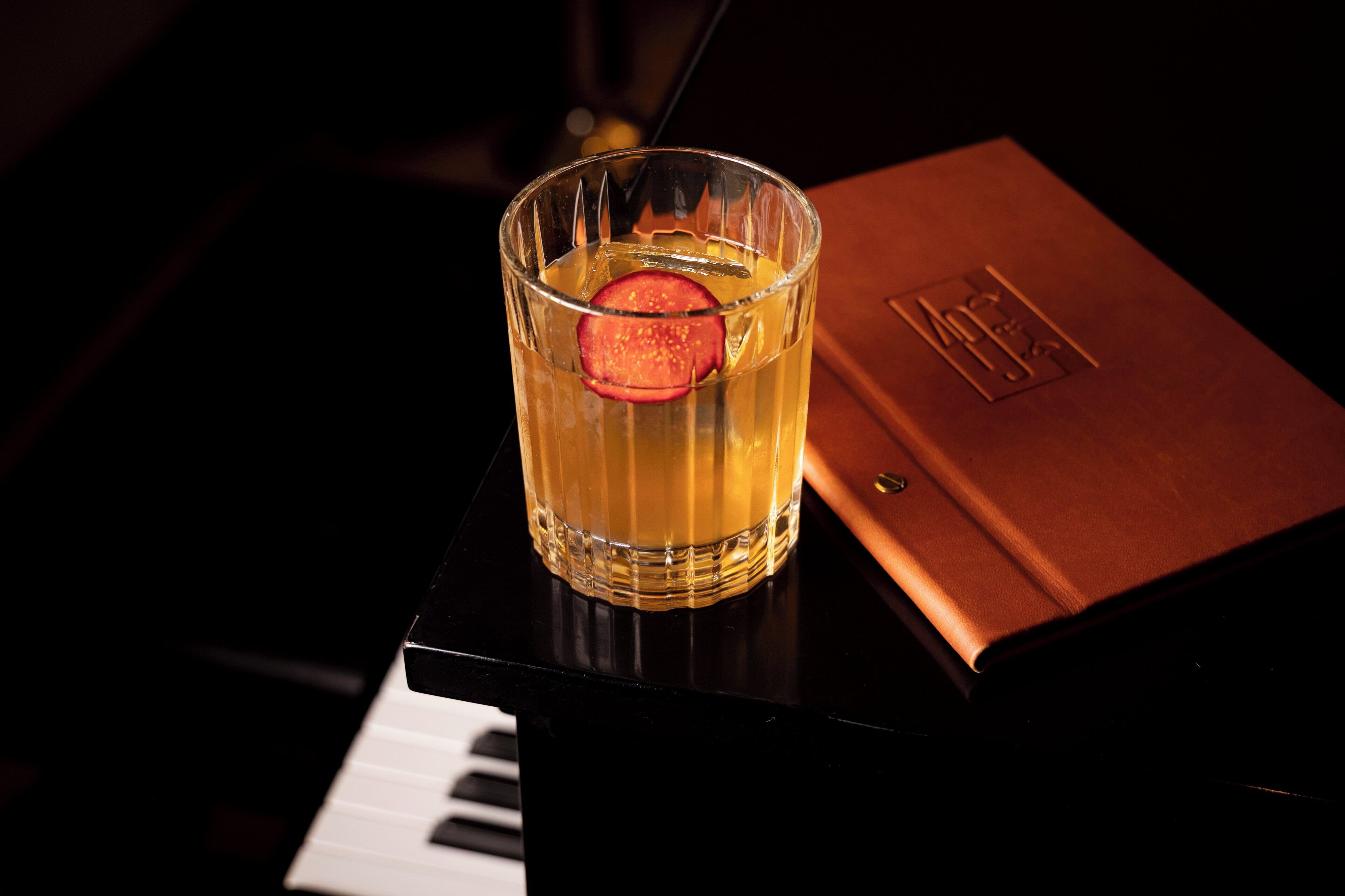 Un verre contenant une tranche de fruit, posé sur une table à côté d’un livre dont le texte est en relief.