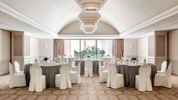 Une salle de conférence avec des tables rondes, des chaises blanches et un tapis à motifs.