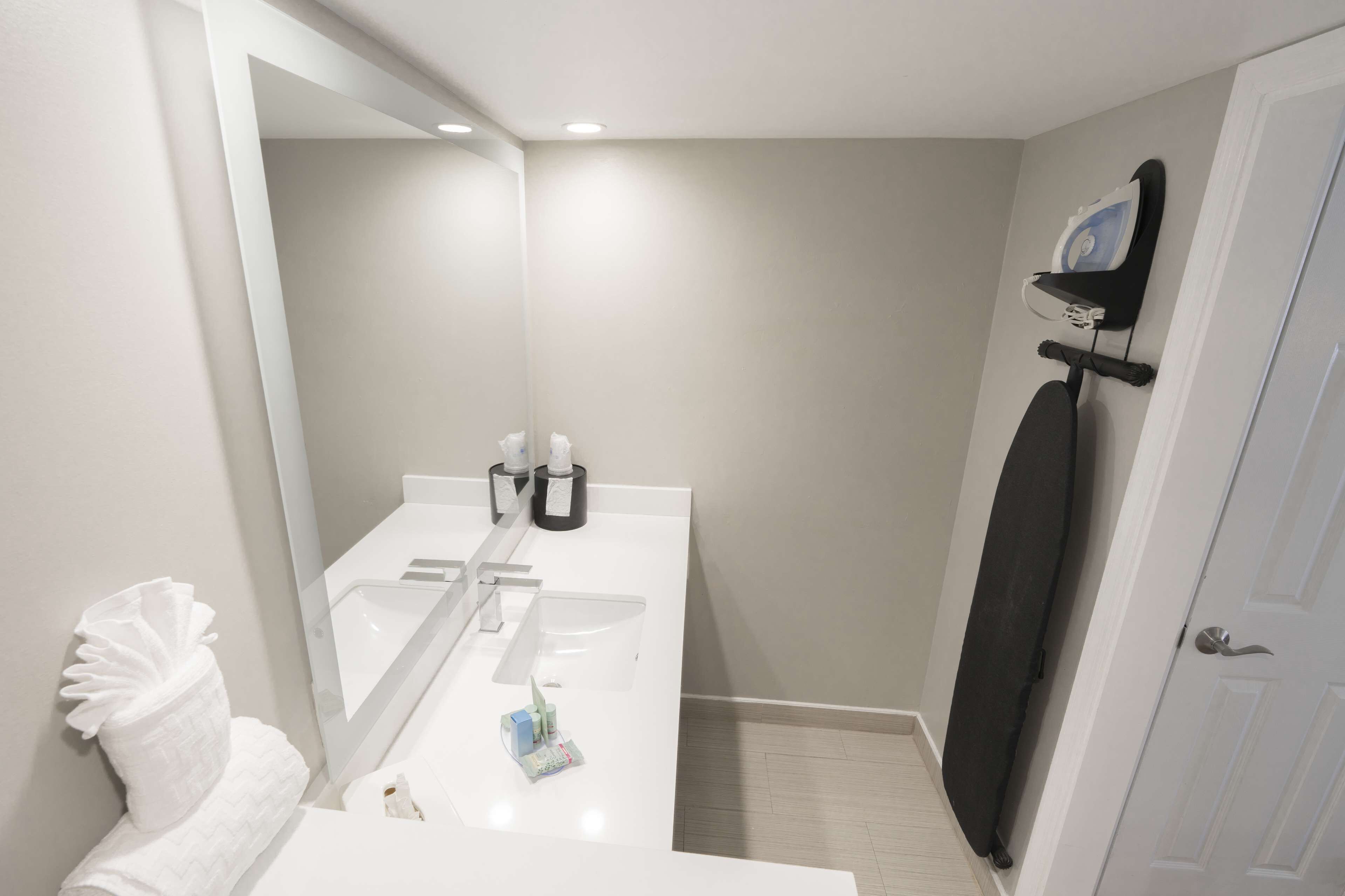 A modern bathroom with a white sink, mirror, and towel rack.
