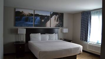 A hotel room with a large bed, two bedside tables, a wall-mounted TV, and a window with curtains.