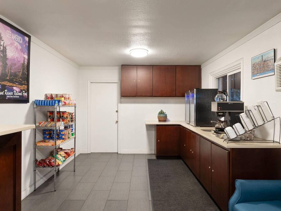 Una cocina compacta con un refrigerador incorporado, una cafetera y una estantería con aperitivos.