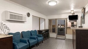 Una sala de estar moderna con un sofá azul, un televisor de pantalla plana y un ventanal con vistas a la ciudad.