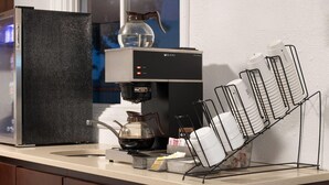 Una cocina con cafetera, hervidor de agua y escurreplatos con platos.