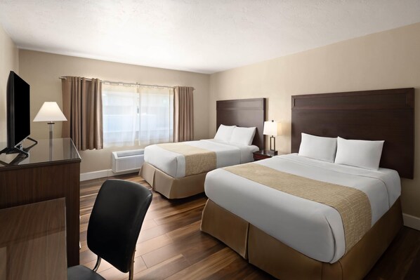 A hotel room with two beds, a desk, a chair, a TV, and a window with curtains.