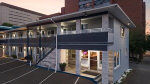 Un hotel de varios pisos con un espacio central abierto, una escalera y un letrero de neón.