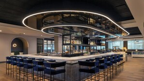 A modern bar area with a central island, bar stools, and a circular light fixture. - Sheraton Boston, a Marriott Hotel (Boston)