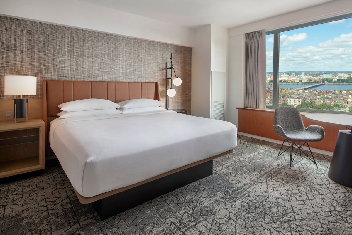Camera d'albergo con un letto grande, una poltrona, una scrivania e vista sulla città.