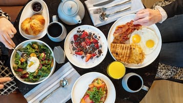 A breakfast table with various dishes, a teapot, and a cup of coffee.
