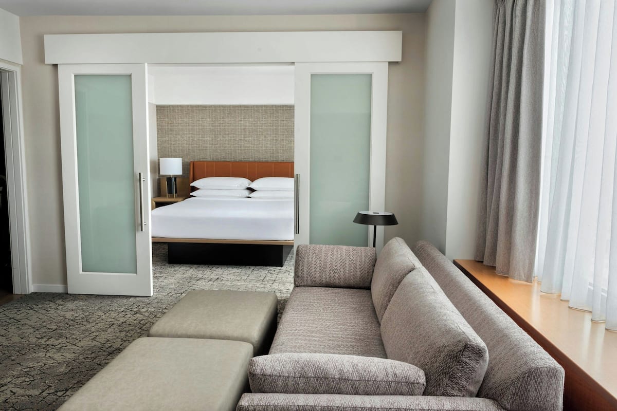 Una camera d'albergo con un letto, un divano, un tavolino e una lampada.
