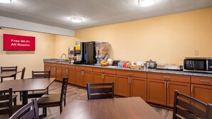 A kitchen with wooden cabinets, granite countertops, and a microwave. There is a sign indicating free Wi-Fi in all rooms. - Red Roof Inn Des Moines (Des Moines)