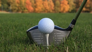 Una pelota de golf sobre la cabeza de un palo de golf.
