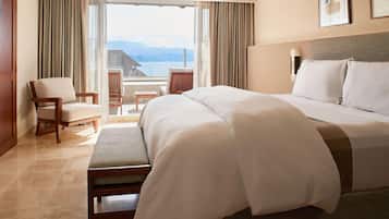 Habitación de hotel con una cama grande, una silla, una mesita y vistas a las montañas desde la ventana.