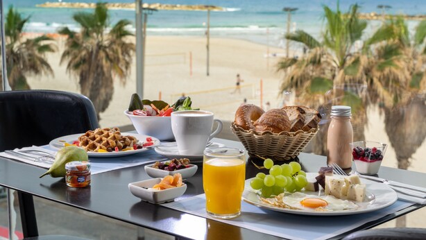 A breakfast table with a view of the beach and ocean. - Crowne Plaza Tel Aviv Beach by IHG (Tel Aviv)