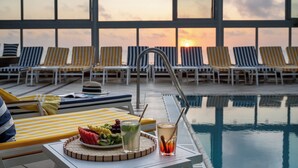 A poolside area with lounge chairs and a table with fruit and drinks. - Crowne Plaza Tel Aviv Beach by IHG (Tel Aviv)
