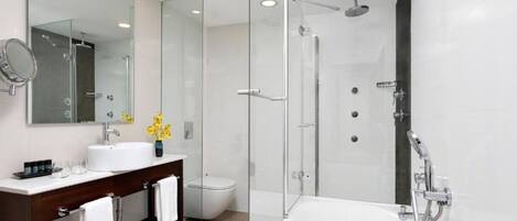 A modern bathroom with a large bathtub, a glass-enclosed shower, and a vanity with a mirror and sink.