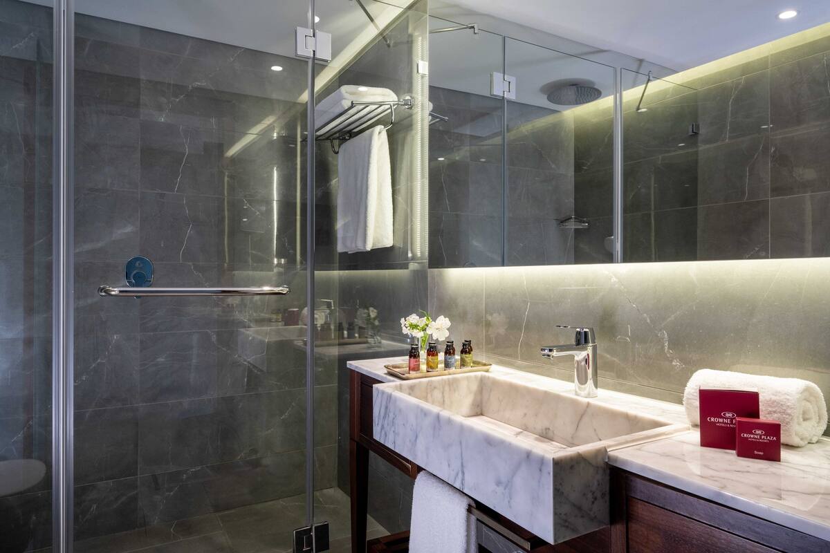 Une salle de bain moderne avec une douche à parois de verre, un lavabo en marbre et un meuble-lavabo avec des articles de toilette.