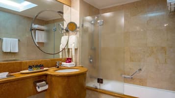 A modern bathroom with a marble sink, a large mirror, and a glass-enclosed shower.