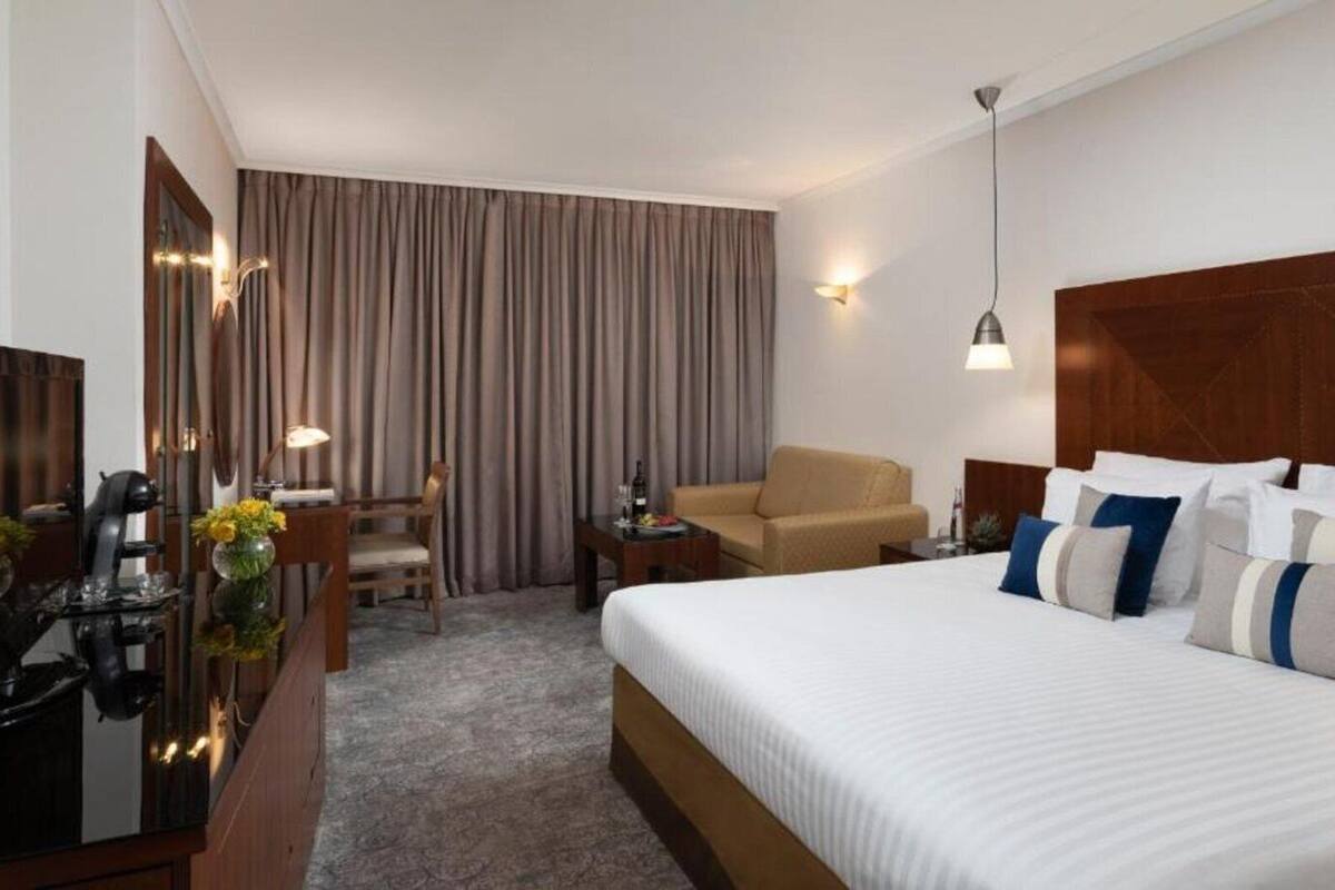 Une chambre d’hôtel avec un grand lit, un bureau, une chaise et un miroir.