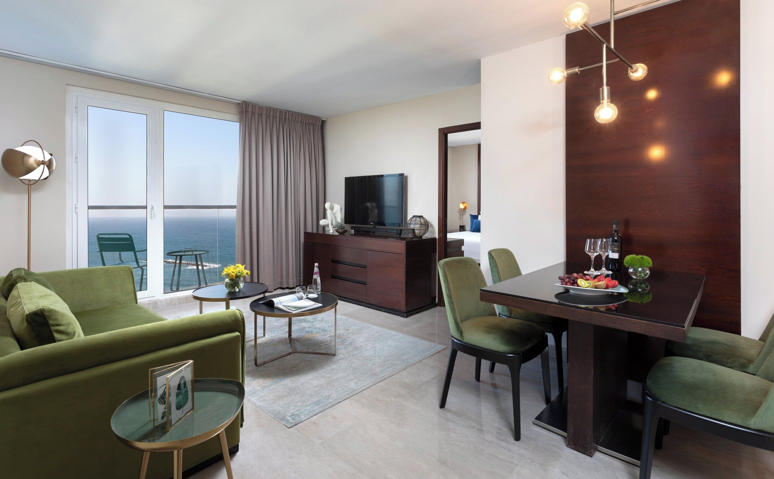 A modern hotel room with a balcony, a dining area, and a living space.