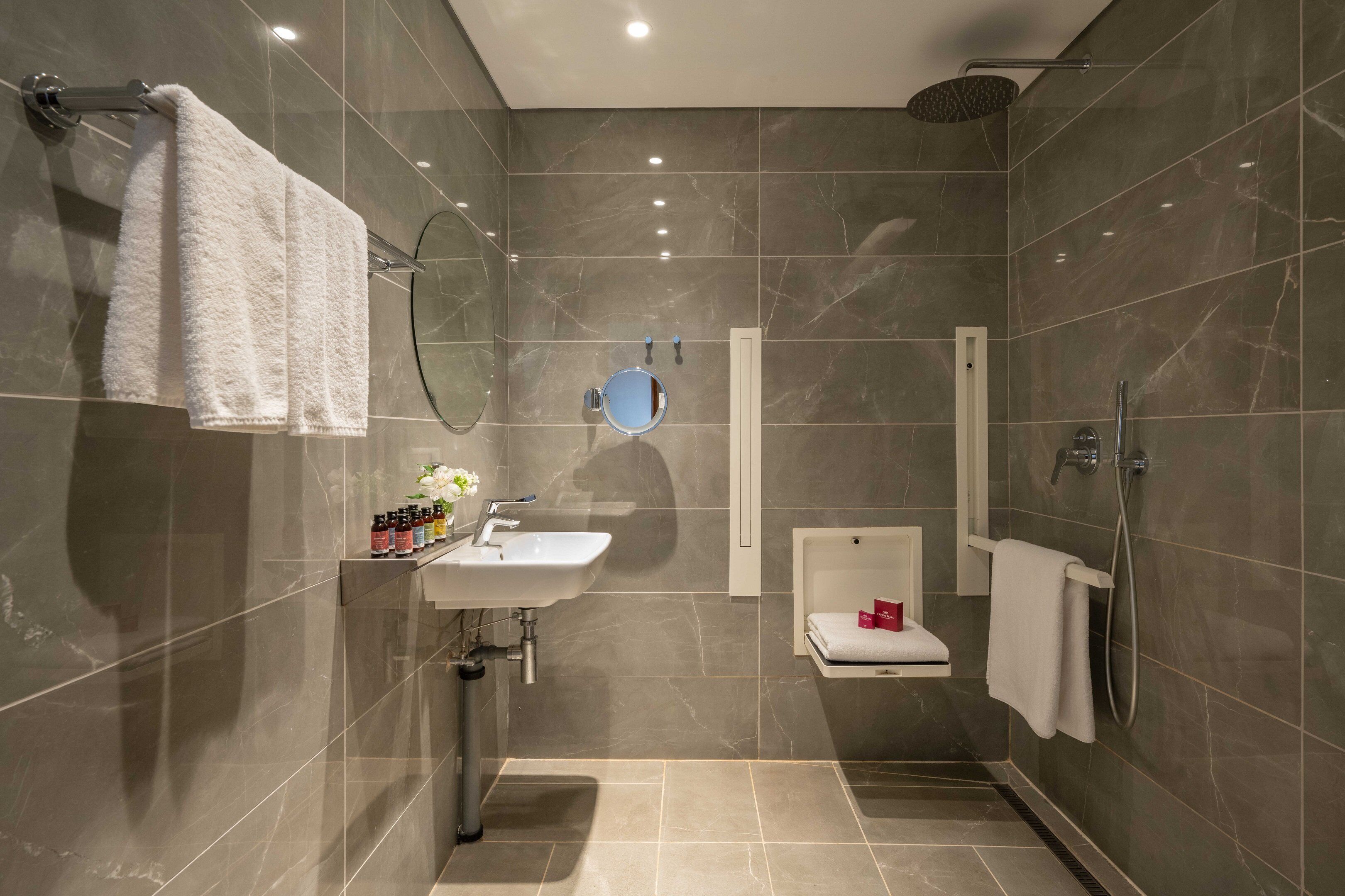 Un baño moderno con lavamanos, espejo y ducha.