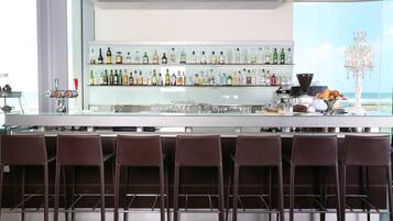A bar area with multiple liquor bottles, glasses, and a coffee machine.