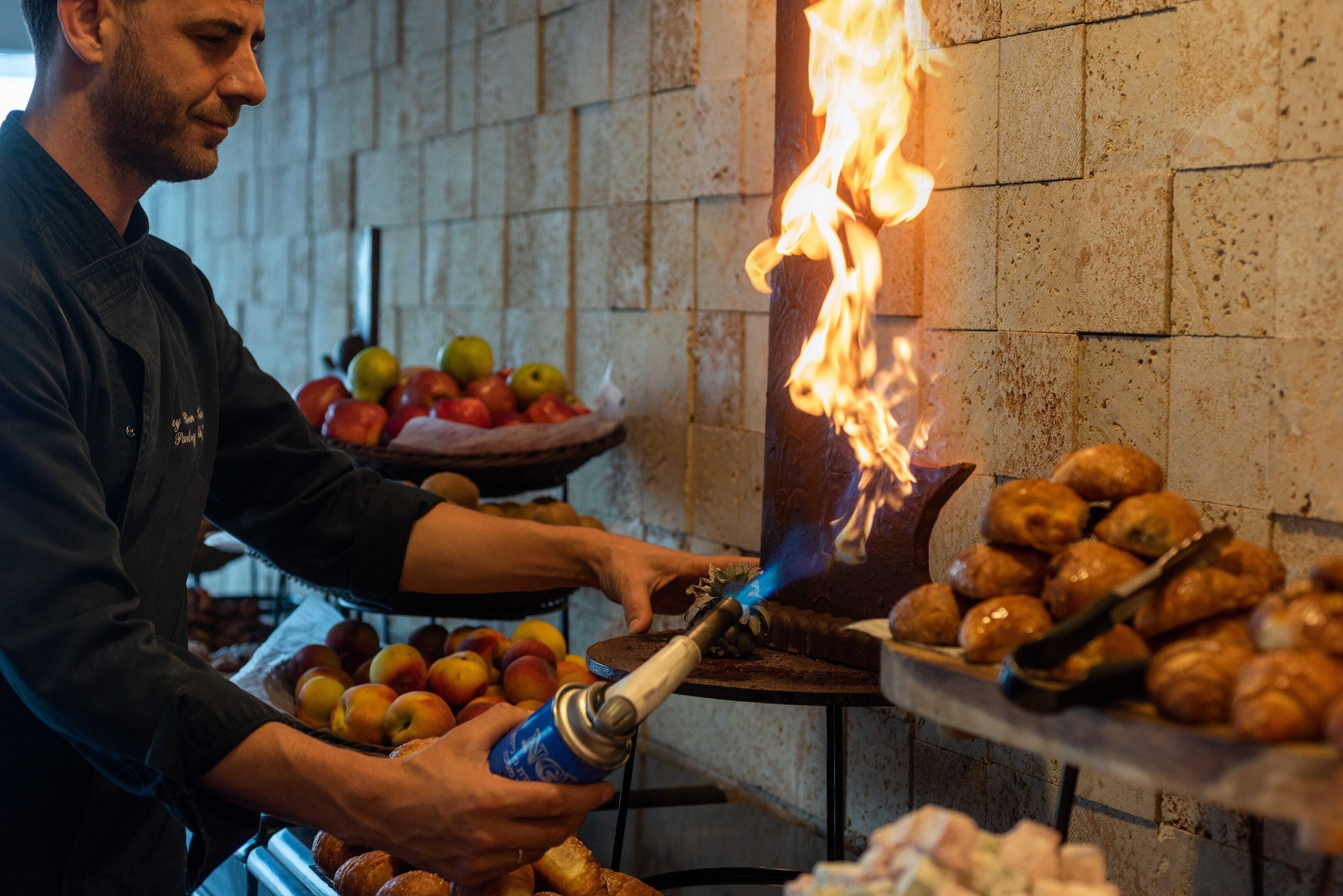 A person using a torch to light a fire in a brick oven.