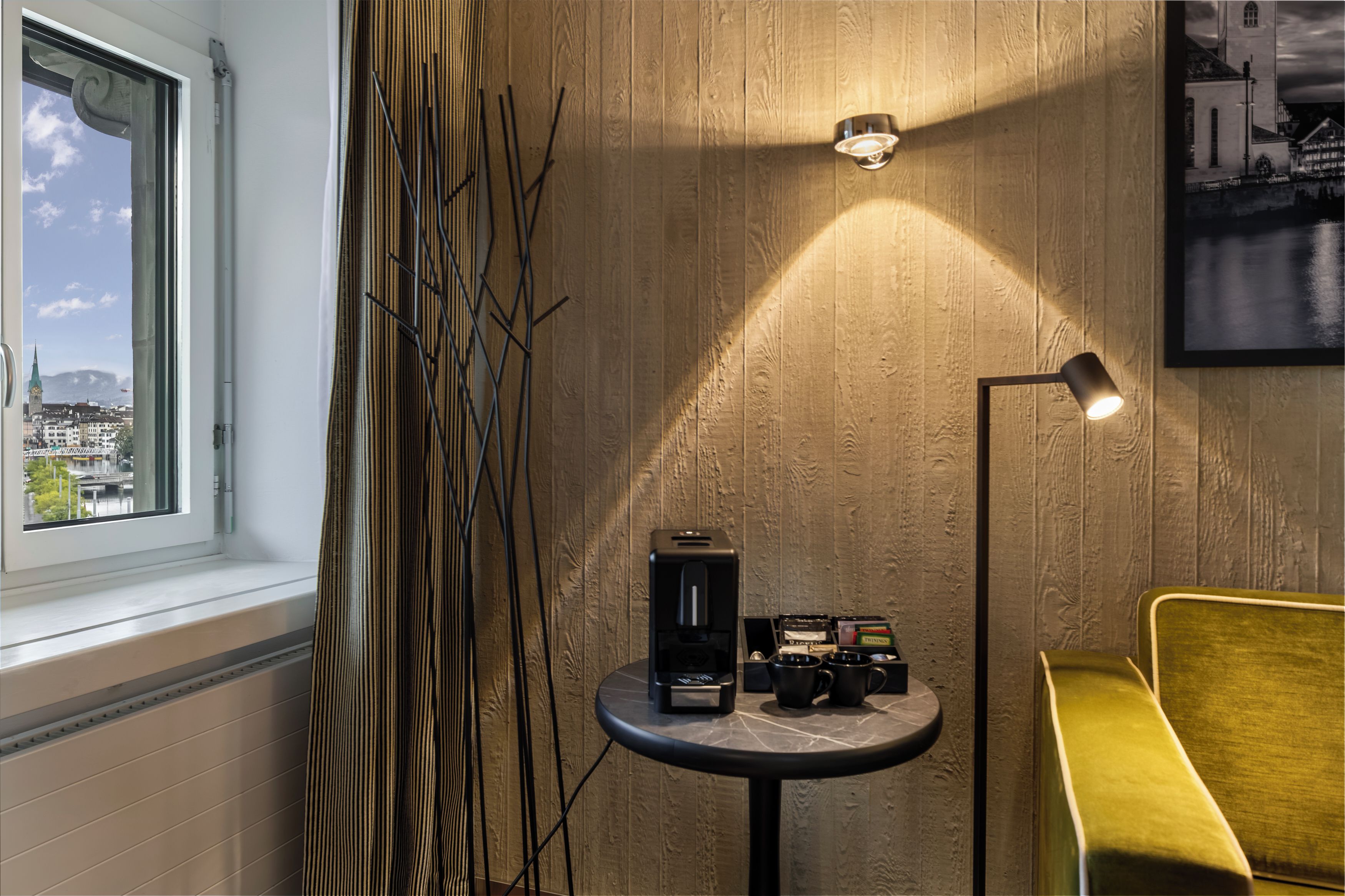 A room with a window, a table with a coffee machine, and a chair.