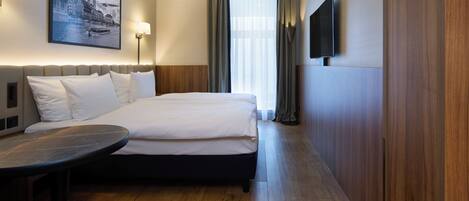 Une chambre d’hôtel avec un lit, un bureau, une télévision et un tableau au mur.