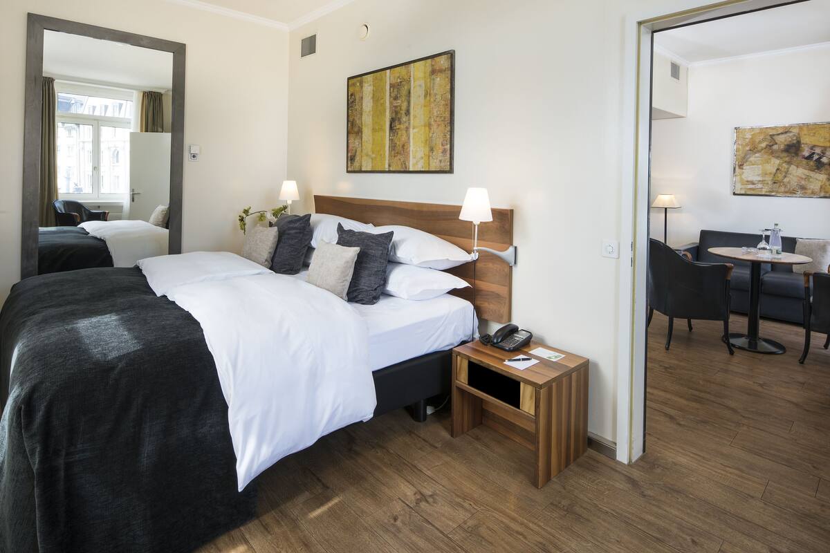 A hotel room with a large bed, bedside tables, a desk, and chairs.