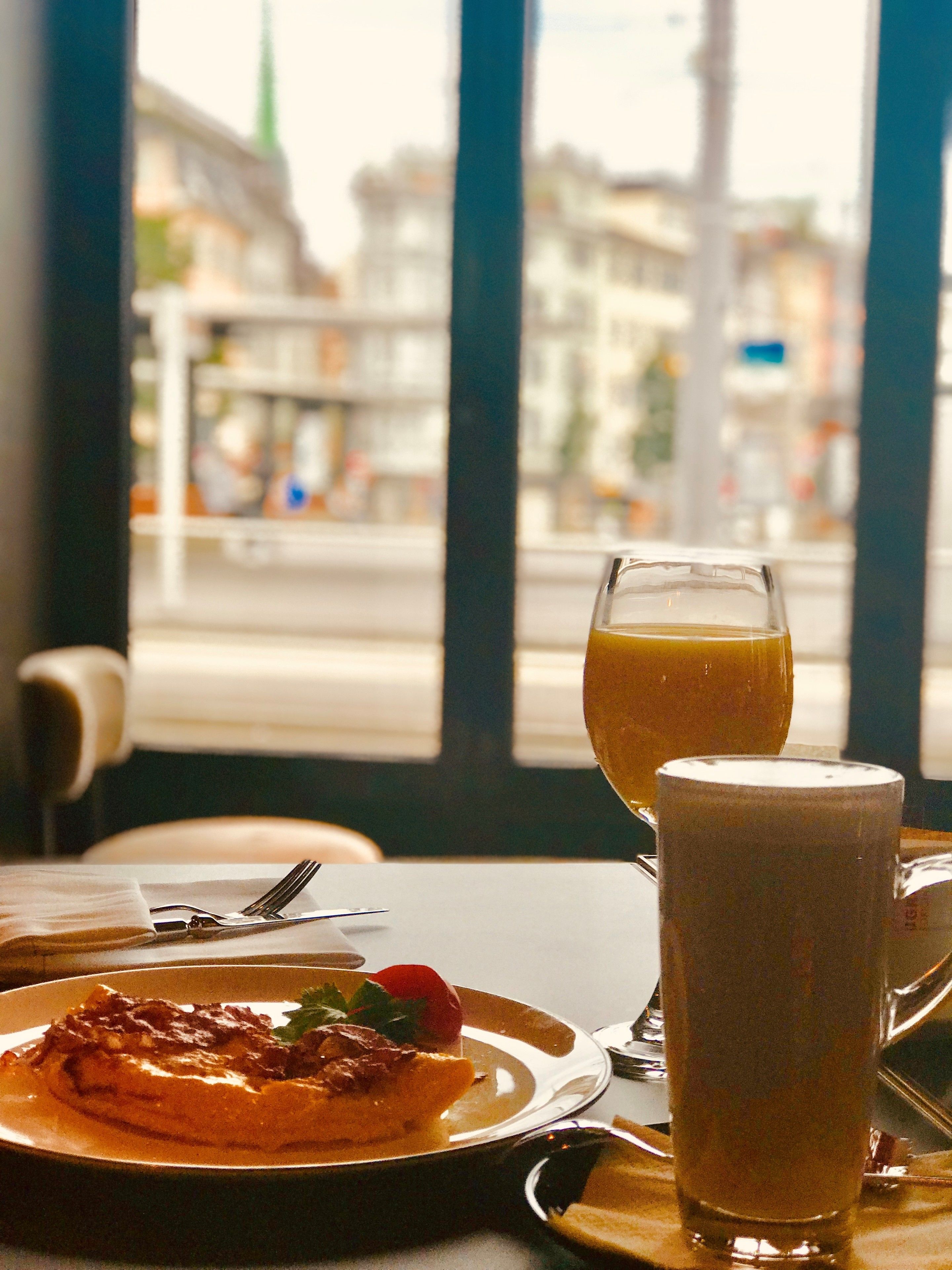 A dining table with a plate of food, a glass of orange juice, and a tall glass of milk.